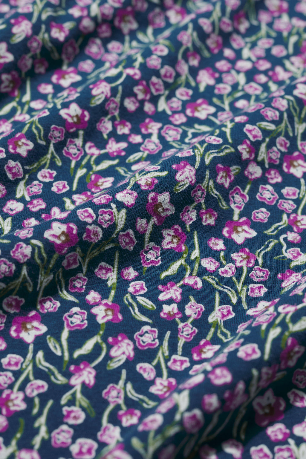 Floral patterned fabric with pink and purple flowers on a blue background